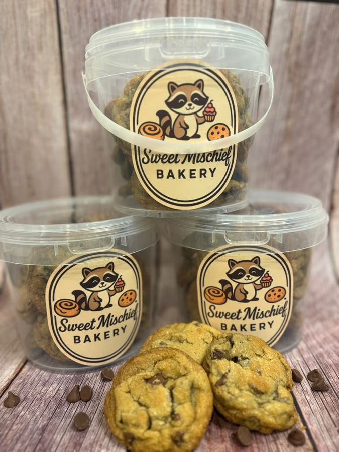 Three Sweet Mischief cookie buckets with cookies on a wooden table