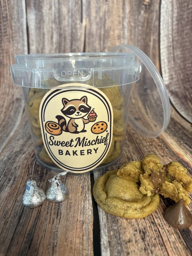 A Sweet Mischief cookie bucket with Hershey's Kisses and a peanut butter cookie beside it