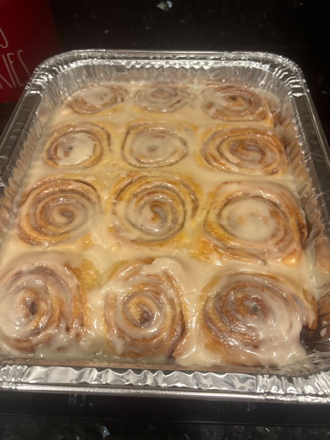 A pan of fresh cinnamon rolls under vanilla icing