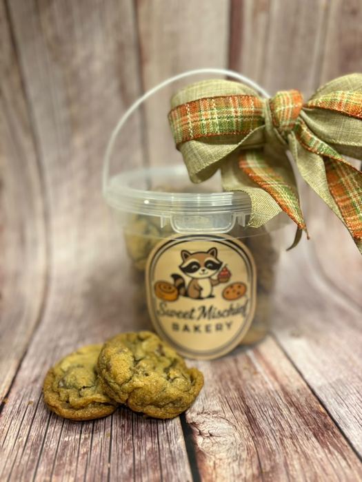 A cookie bucket tied with a ribbon beside cookies